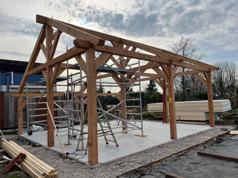 Constructie in douglas hout van een buitenverblijf in aanbouw, met asymmetrische kap en schoren