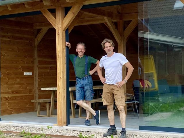 Houten tuinkamer met glazen schuifwanden en pannendak, met de twee makers op de voorgrond