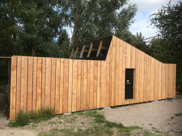 Modern atelier met verticale gevelbekleding van lariks en daklichten